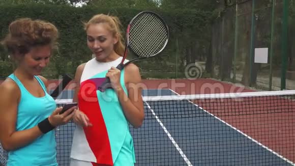 两个网球女孩一边讨论一边分享智能手机视频的预览图