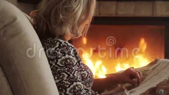 坐在壁炉旁的女人在椅子上的织物上刺绣图案视频的预览图