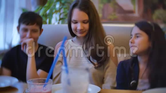 在咖啡馆里交流的女孩是朋友儿童青少年坐在咖啡馆快餐室内慢动作视频视频的预览图