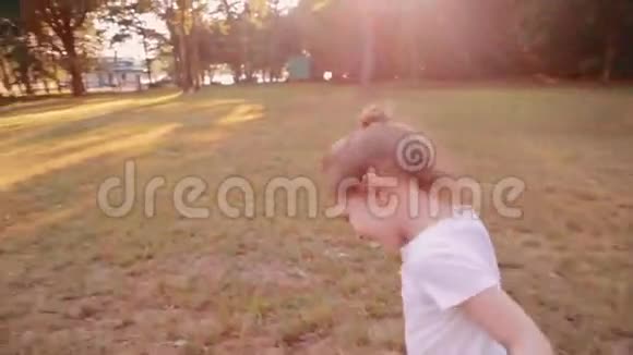 一个快乐的小女孩在阳光明媚的夏天在公园的一条路上跑步后景慢影视频的预览图