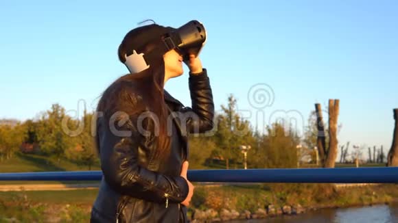 日落时分码头上戴着虚拟现实眼镜的年轻女子视频的预览图