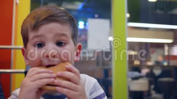 男孩子在快餐店吃汉堡和炸薯条加酱汁小男孩在孩子们吃东西时胃口大开视频的预览图