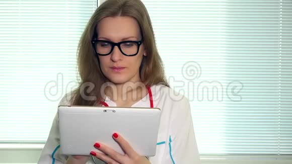 女医生用平板电脑看着相机微笑着视频的预览图