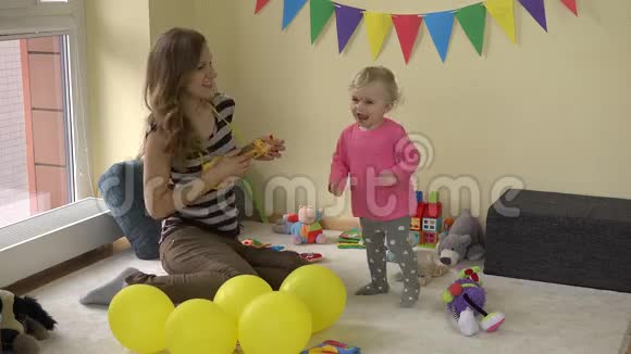 妈妈在玩玩具吉他可爱的女婴在派对上的玩具间跳舞视频的预览图