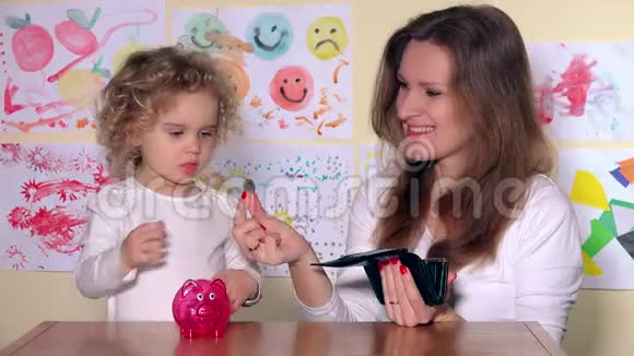 快乐的母女把硬币放进储蓄罐视频的预览图