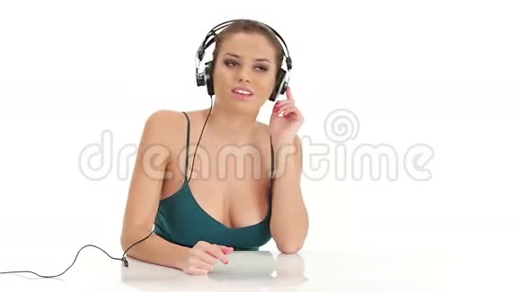 一位年轻的美女在听大型立体声耳机音乐视频的预览图
