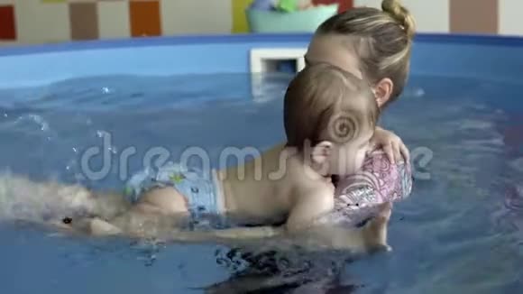 一个小孩子和教练在游泳池里洗澡视频的预览图
