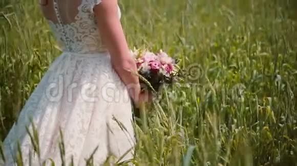 一位新娘站在麦田里手里拿着一束鲜花穿上一件漂亮的蕾丝婚纱视频的预览图