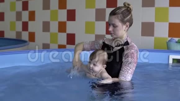一个小孩子和教练在游泳池里洗澡视频的预览图