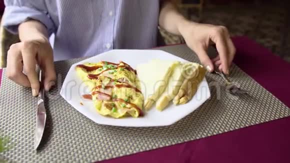 女人吃火腿和烤面包的煎蛋吃早餐的特写视频的预览图