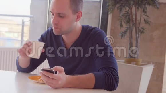 有智能手机的年轻人在咖啡馆吃三明治视频的预览图