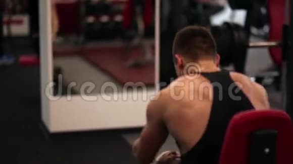 坐在椅子上休息的运动员的后视图运动的男人在健身房锻炼后休息视频的预览图