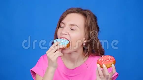 年轻漂亮的吃甜甜圈暴饮暴食的概念视频的预览图