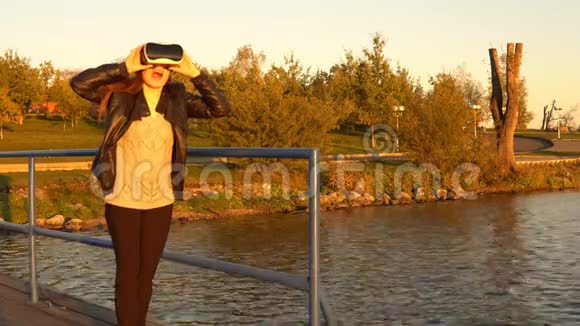 日落时分码头上戴着虚拟现实眼镜的年轻女子视频的预览图