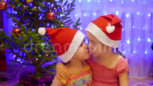 两个姐妹在圣诞晚会上拥抱和亲吻背景圣诞杉木的灯光和花环视频的预览图