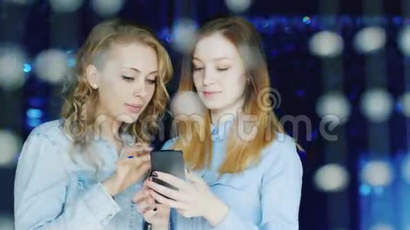 两个年轻的女性朋友在夜总会用智能手机阅读信息视频的预览图