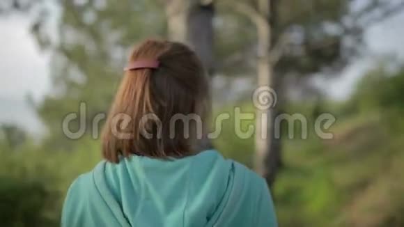 年轻漂亮的女人在森林里的树间散步夏季景观视频的预览图