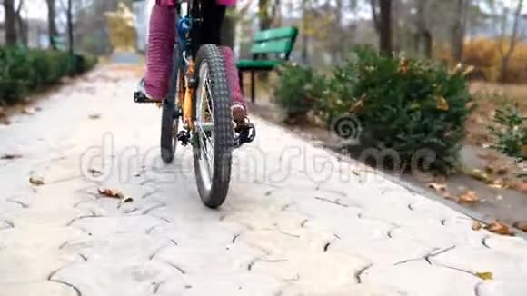 一个高加索儿童在秋季公园骑自行车公园里骑着黑色橙色自行车的小女孩视频的预览图