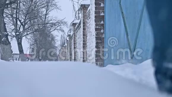 冬天人们穿过一座古老的砖围栏的雪城穷人在冬天的户外雪地里散步视频的预览图