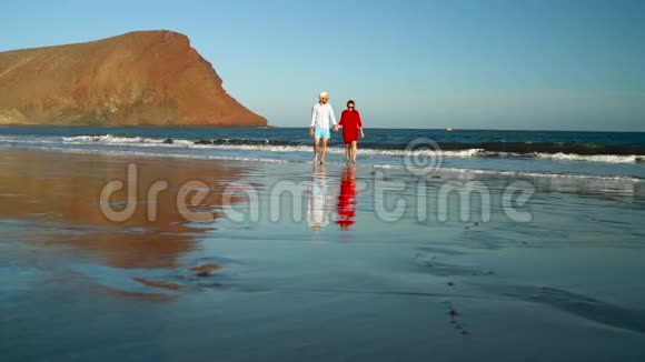 恋爱中的夫妻无忧无虑地走到海滩上的水里西班牙加那利群岛特内里费海岸图片视频的预览图