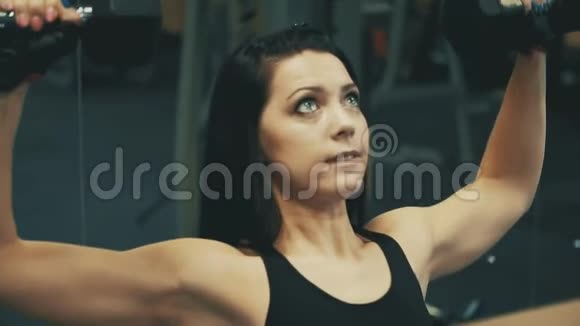年轻女子在健身馆用哑铃做运动健康生活方式视频的预览图