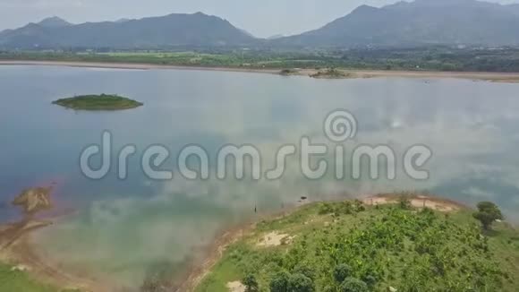飞行摄像机在湖上移动在高地之间有绿色的河岸视频的预览图