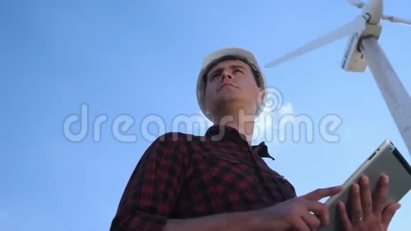 男工程师正在检查平板上的风力涡轮机晴天和云彩一个男人穿着格子衬衫视频的预览图