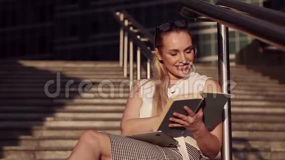 一位年轻成功的商业女性在商业中心中间阅读书籍的肖像视频的预览图