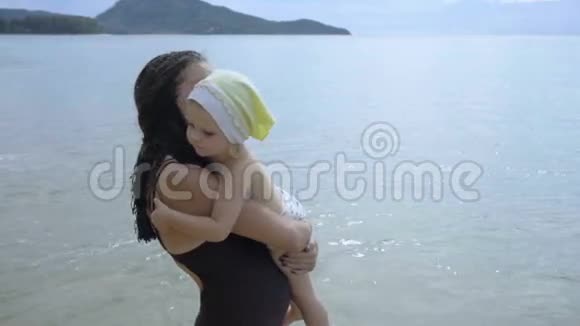 母亲和小女儿肩并肩走在海岸线上视频的预览图