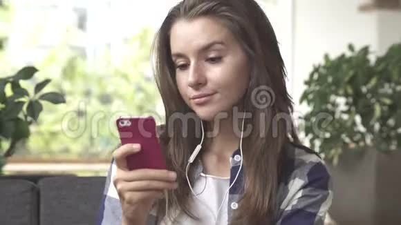 女人用耳机在智能手机上听音乐视频的预览图