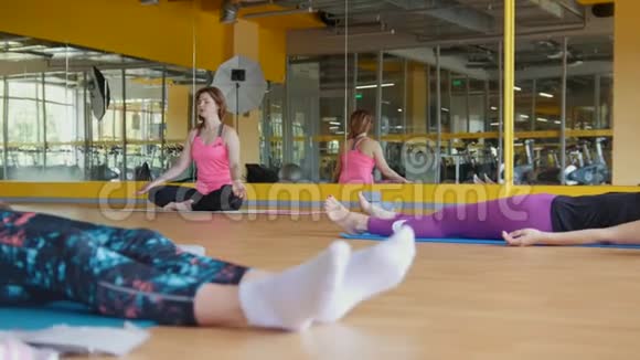 健身房里的瑜伽教练为一群女人展示莲花姿势视频的预览图