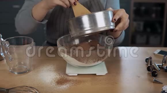 近距离观看年轻女子称可可添加面粉女孩用厨房的天平碗和筛子做这个视频的预览图