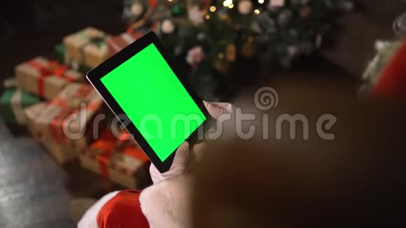 圣诞老人选择iPad上的礼物带绿屏的平板电脑视频的预览图