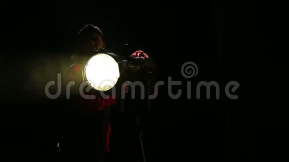 一个年轻的女性照明者从聚光灯引导一束光视频的预览图