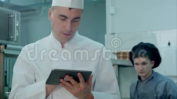 厨师在专业厨房里寻找数码平板的食谱视频的预览图