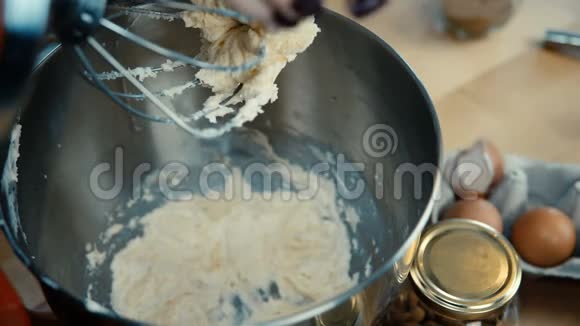 近距离观看女性手添加鸡蛋并打开搅拌机女人在厨房的碗里煮面团视频的预览图