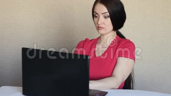 一个女孩坐在笔记本电脑前惊讶地看着显示器视频的预览图