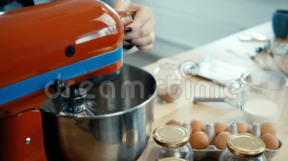 近距离观看年轻女性的手混合配料在大碗与搅拌机厨房里有女人做饭视频的预览图