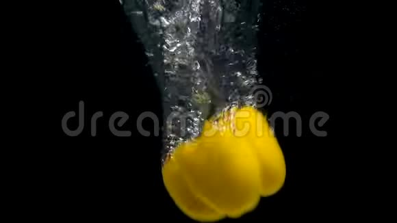 黑色背景下黄色胡椒在水中落下的脚印视频的预览图