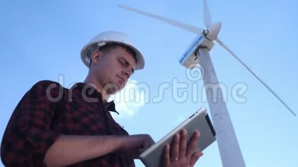 男工程师正在检查平板上的风力涡轮机晴天和云彩一个男人穿着格子衬衫视频的预览图