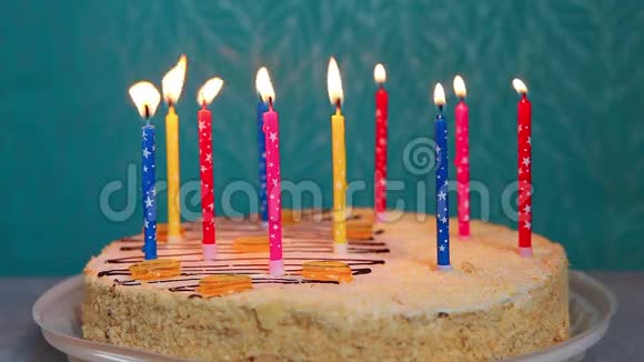 生日快乐蛋糕蓝色背景下点燃五颜六色的蜡烛视频的预览图