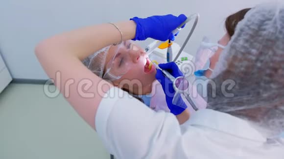牙科保健员为牙科的年轻妇女做超声波清洁牙齿视频的预览图