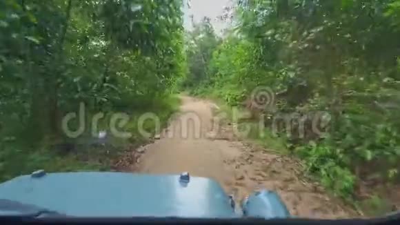 军用吉普车沿丛林间肮脏的地面道路行驶视频的预览图