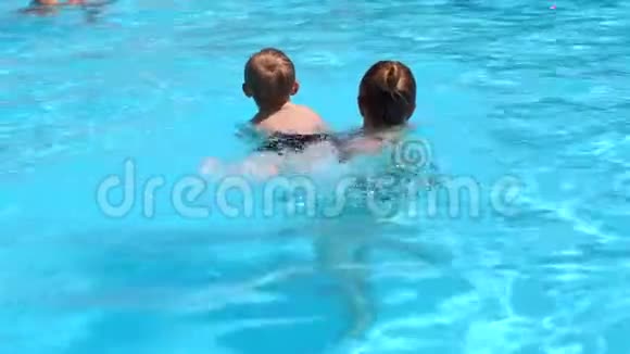 一位年轻的母亲在夏天教她的小儿子在游泳池里游泳视频的预览图
