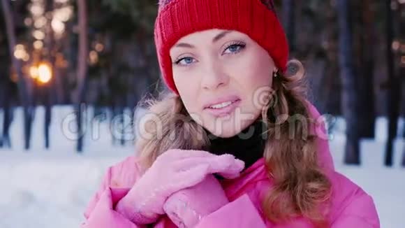 冬天森林里一个年轻迷人的白种人女人的肖像用粉红色手套温暖双手视频的预览图