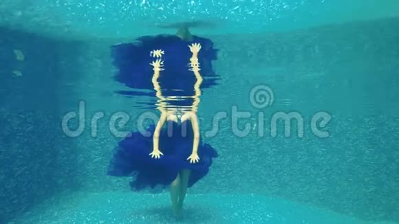 穿着蓝色长裙的漂亮女孩在泳池水下摆姿势拍照视频的预览图