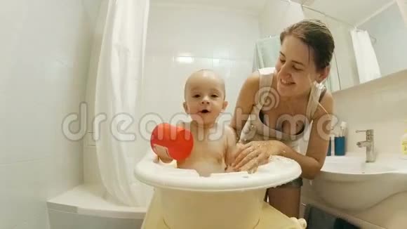 欢快的一岁小男孩在浴缸里和妈妈一起泼水视频的预览图