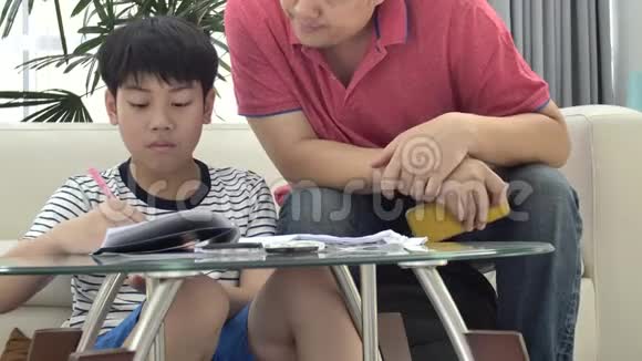 亚洲父子在客厅的桌子上做作业视频的预览图