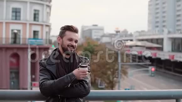 一个留着胡须和时髦发型的时髦帅哥兴高采烈地笑着拿着外卖咖啡或茶慢节奏视频的预览图
