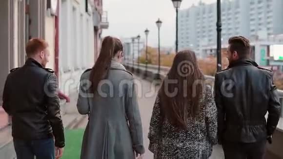 两个时髦的女孩和两个时髦的男人在城里散步背景的建筑物慢影稳拍后景视频的预览图